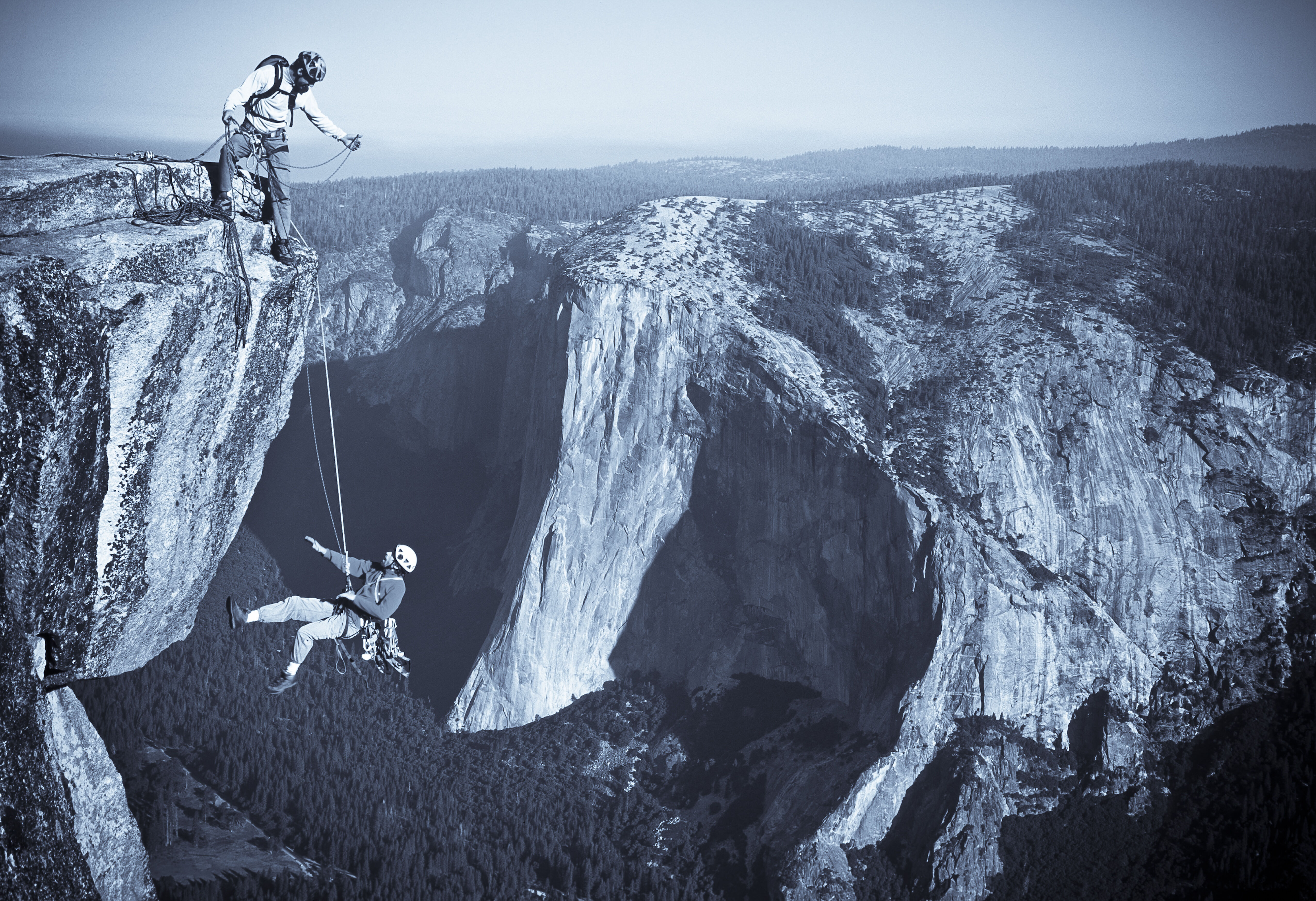 Team of rock climbers struggle up a challenging cliff.