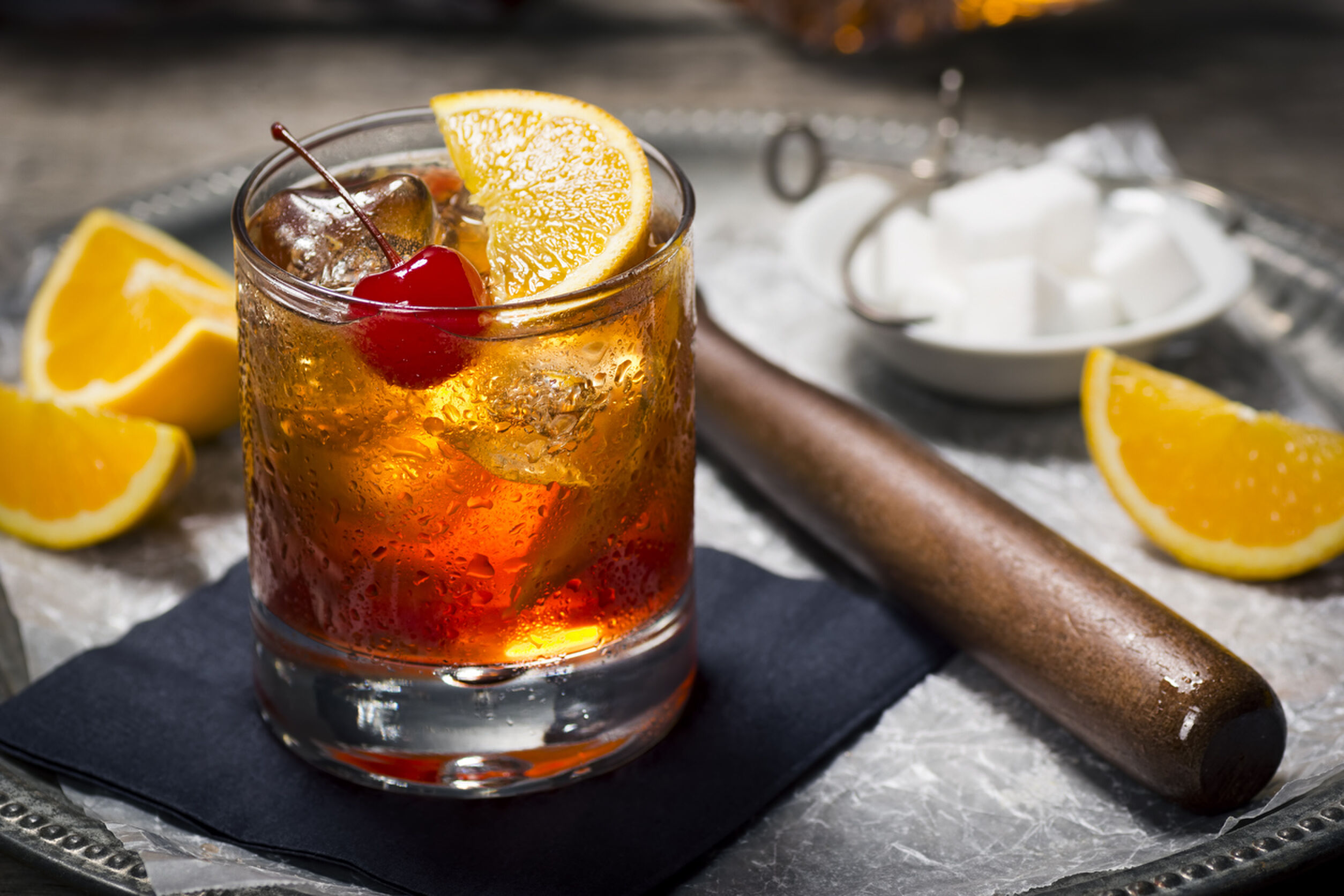 "The Old Fashioned is most commonly made by muddling sugar cubes with bitters, a cherry and an orange wedge or peel. Usually a splash of water or soda water is added along with ice, bourbon (or rye) and a garnish."