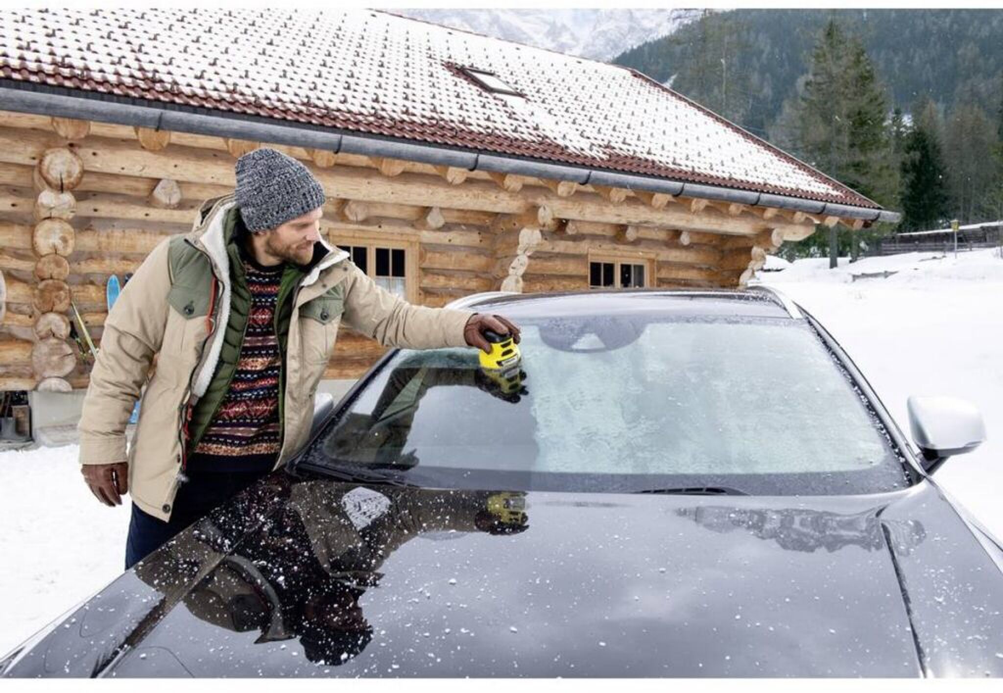 Een man die zijn autoruit ijsvrij maakt met een elektrische ijskrabber van K&auml;rcher