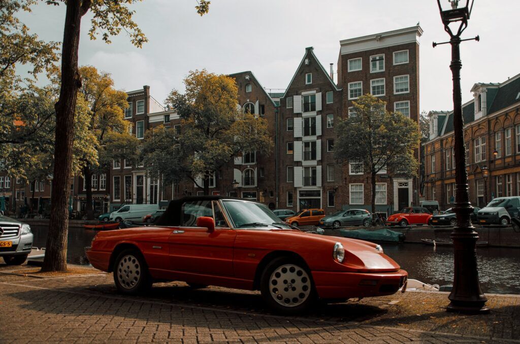 Een rode auto geparkeerd in Amsterdam overdag