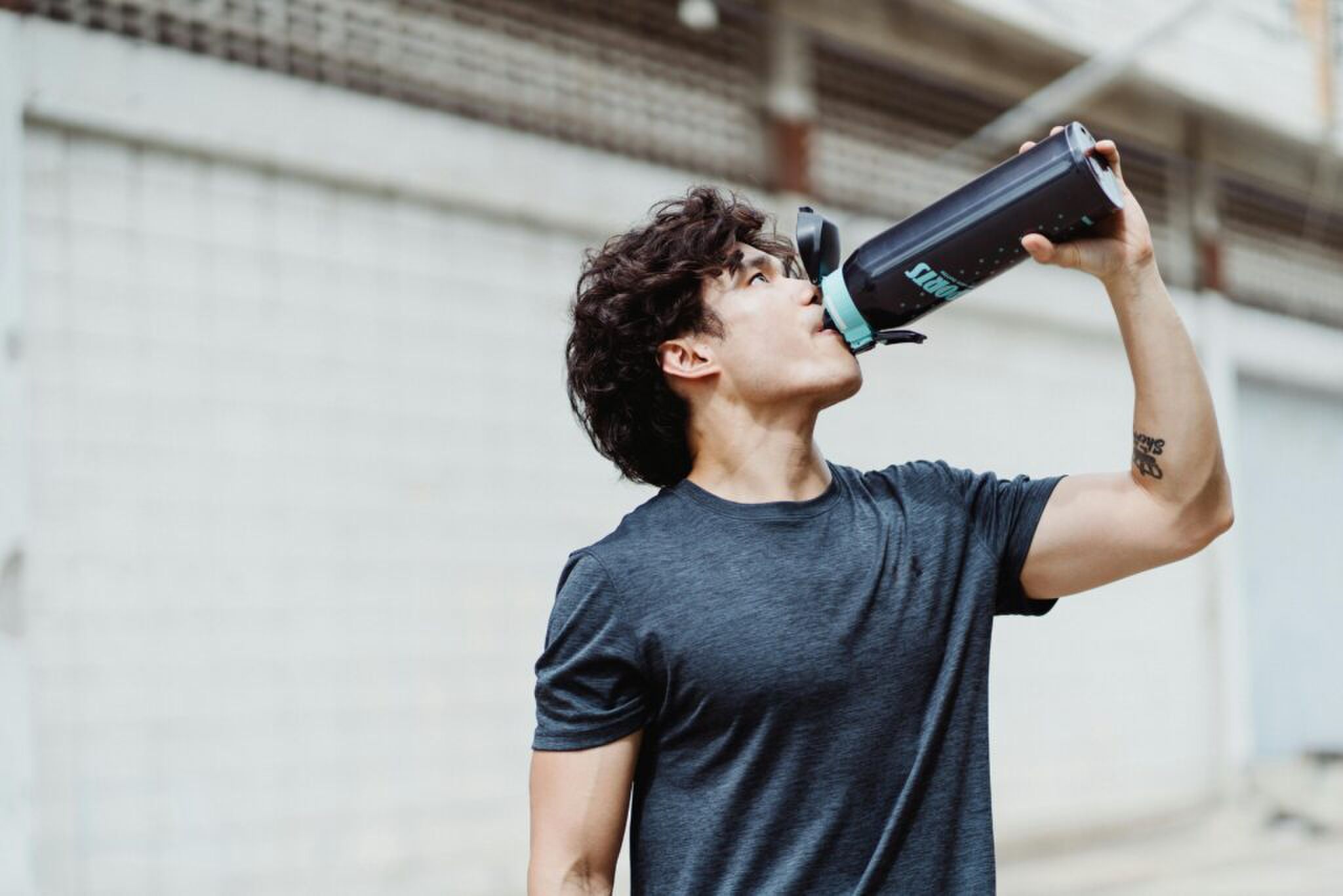 een man die een bidon vol met pre-workout poeder aan het drinken is, hij heeft overduidelijk niet geluisterd naar de slaapexpert