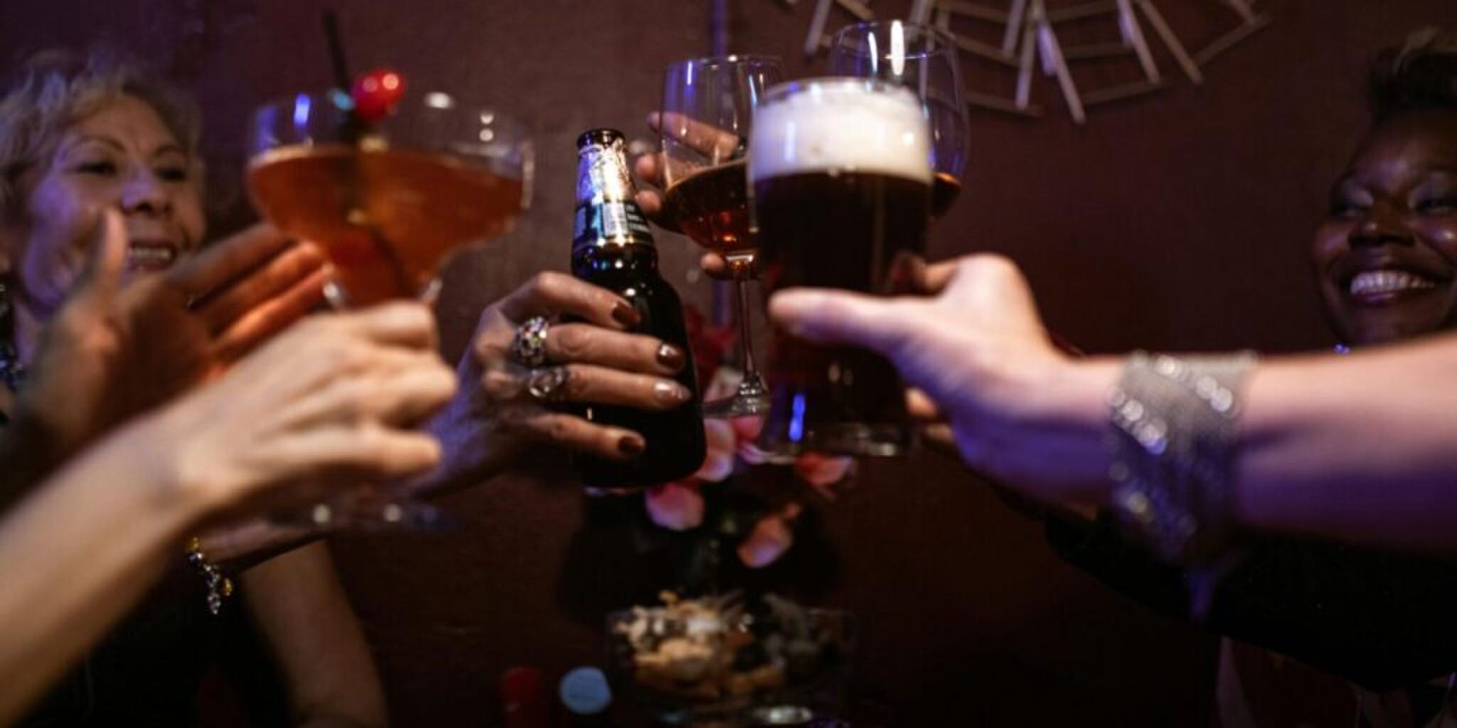 een paar handen met glazen alcohol erin die proosten