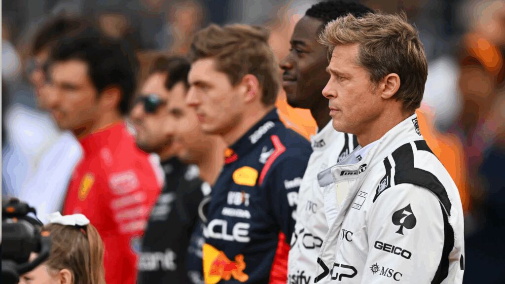 Een shot uit F1: The Movie, met op de voorgrond acteurs Brad Pitt en Damson Idris, en daarachter wat echte coureurs uit de F1 zoals Max Verstappen zelf