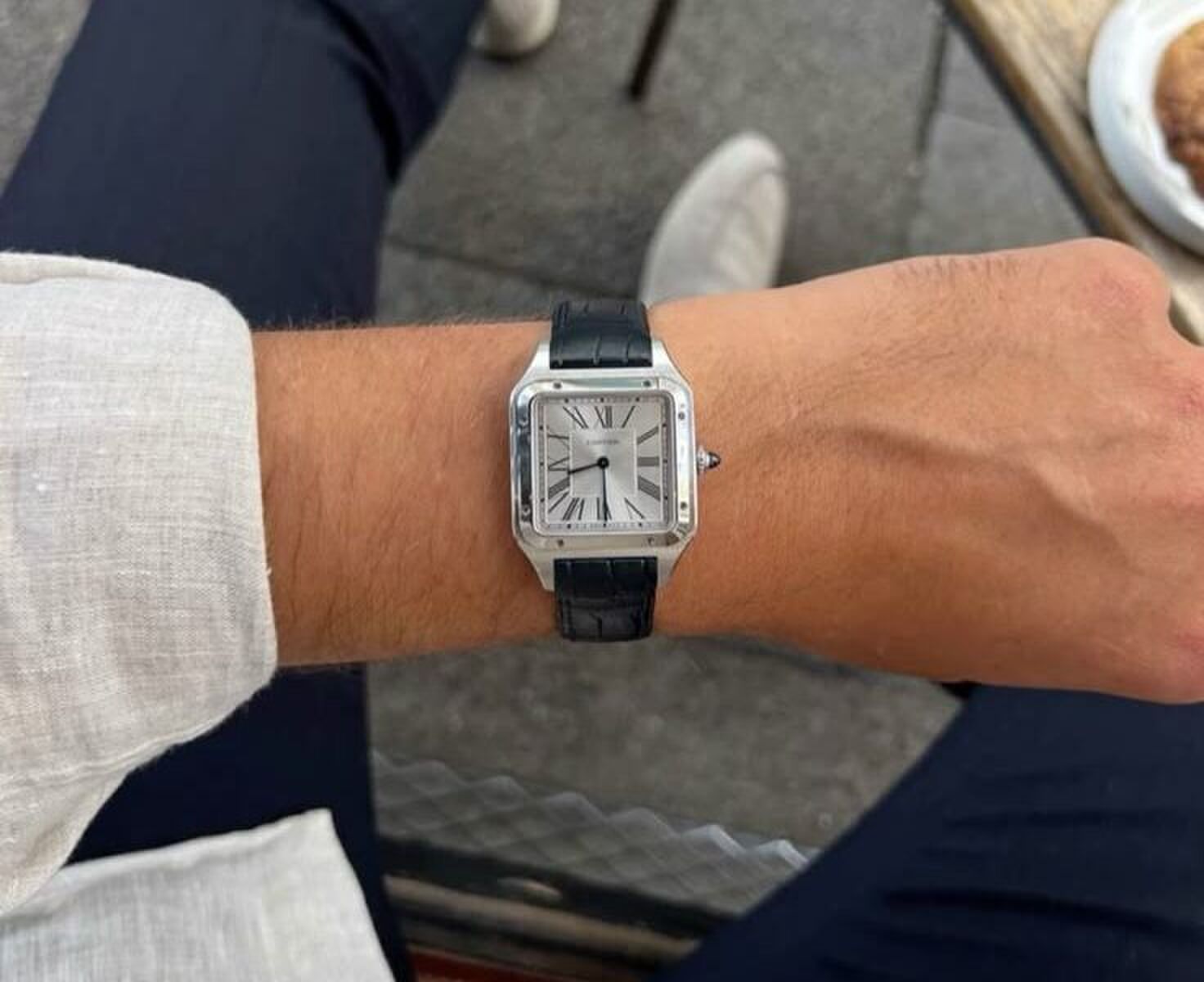De pols van een man die zijn schitterende horloge met leren band showt