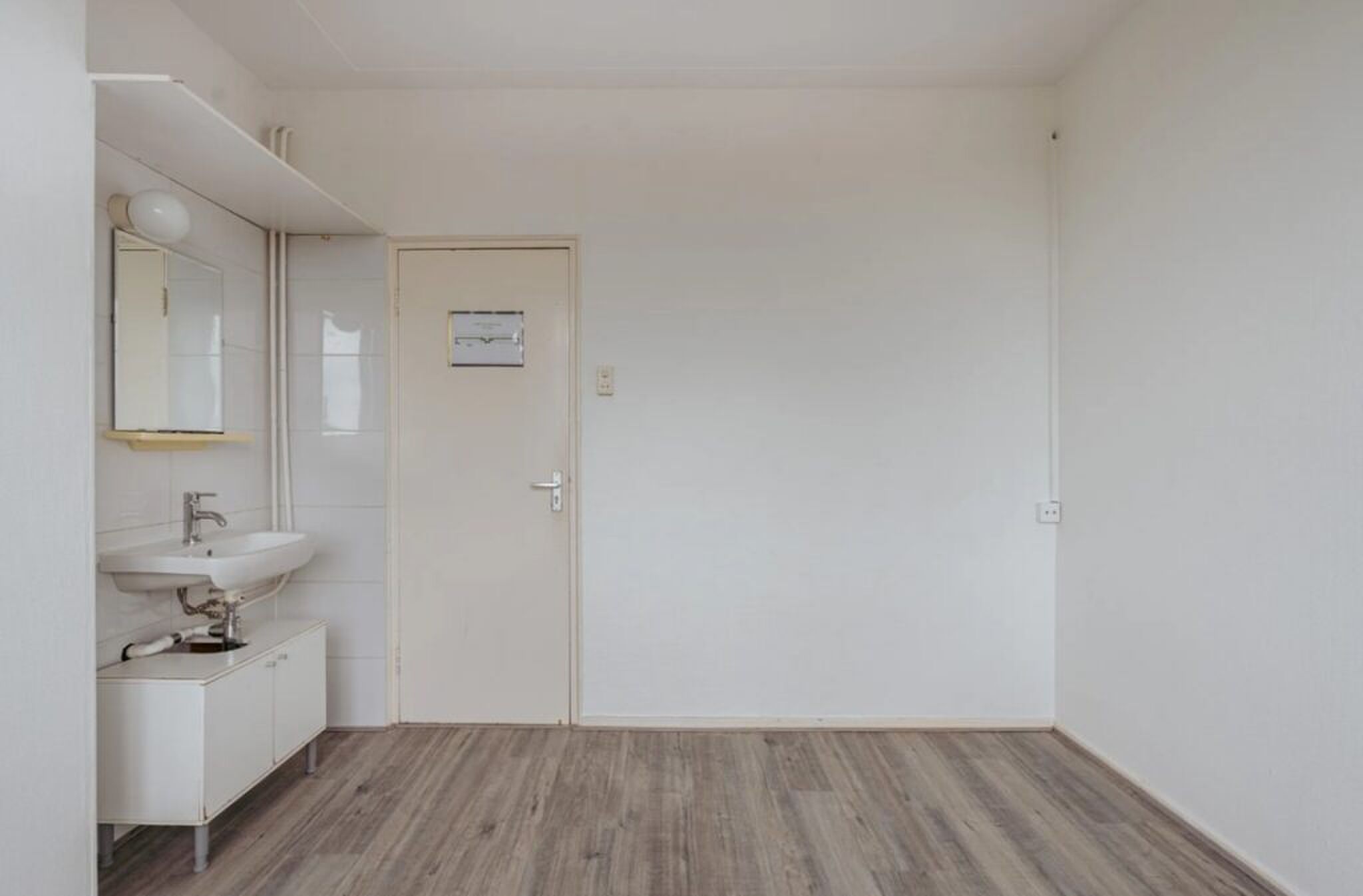 De wasbak en voordeur.