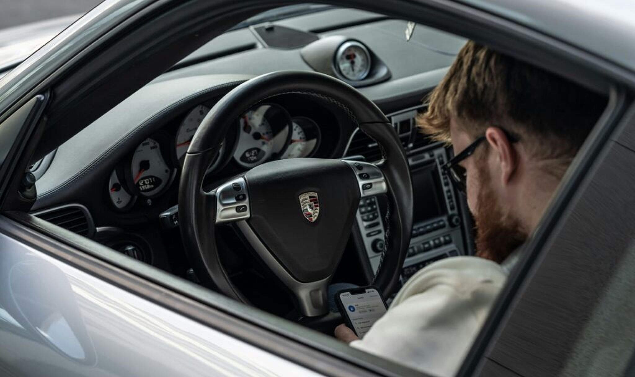 Een autotester die zijn salaris verdient door in een Porsche te zitten.