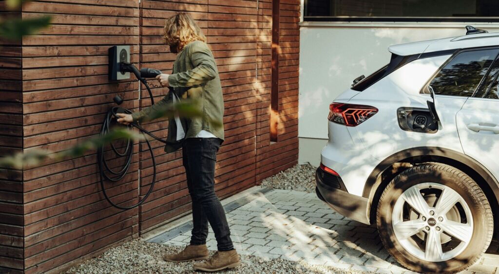 Een man die zijn elektrische auto gaat opladen.