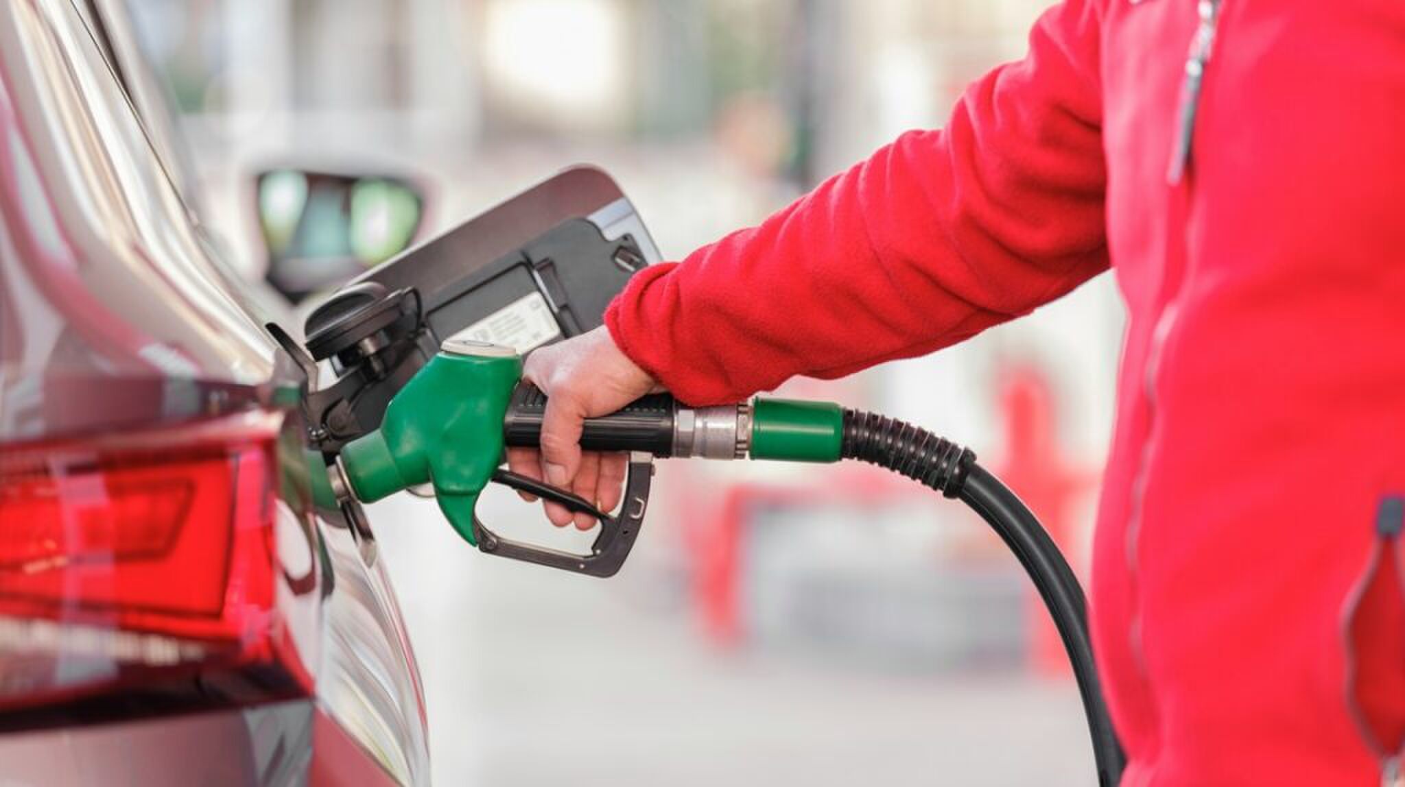 Een man die zijn auto voltankt.