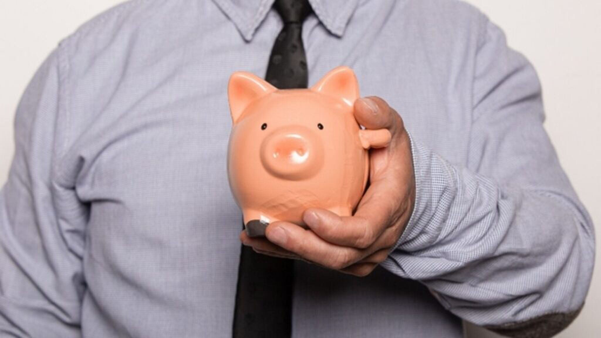 Een man met een spaarvarken in zijn hand.