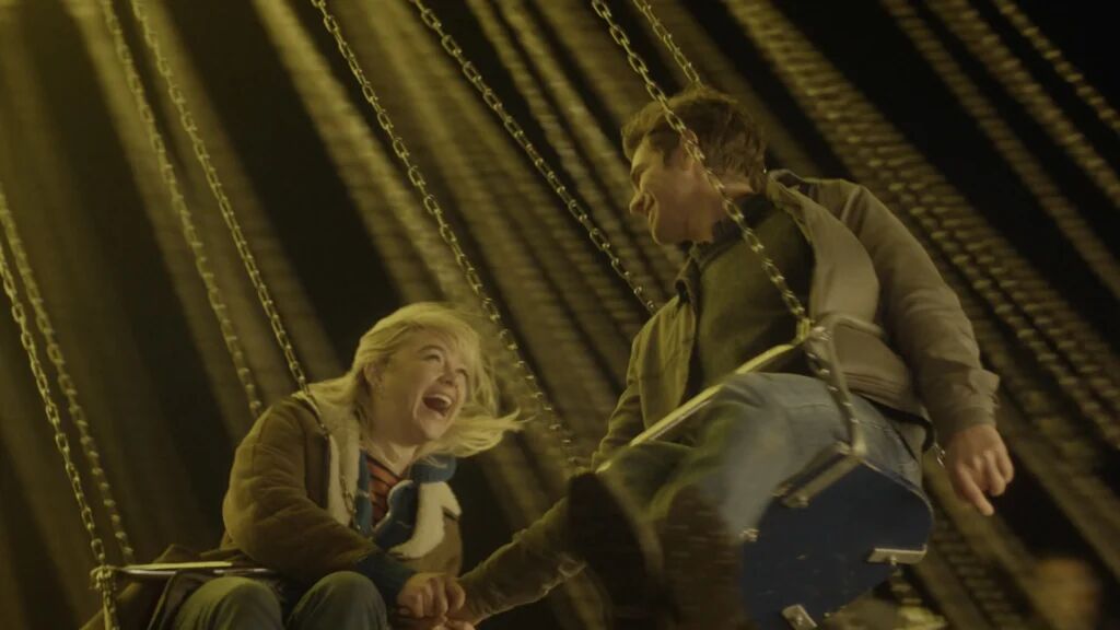 Een man en vrouw die in een draaimolen zitten.