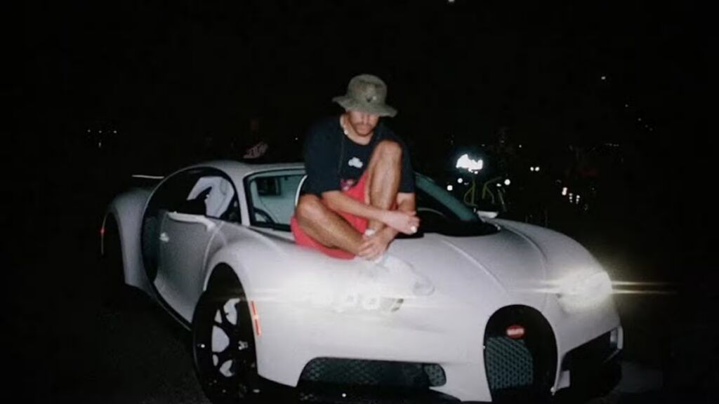 rapper Bad Bunny op de motorkap van zijn Bugatti