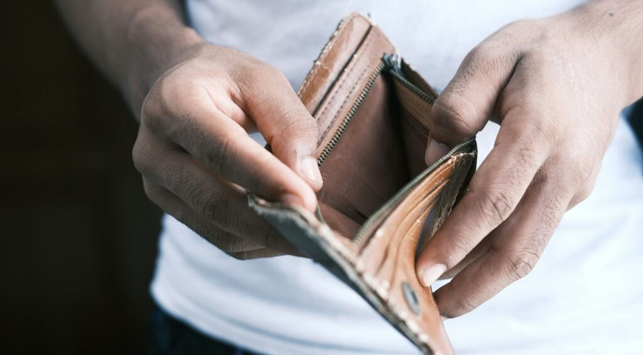 Een man met een lege portemonnee in de handen.