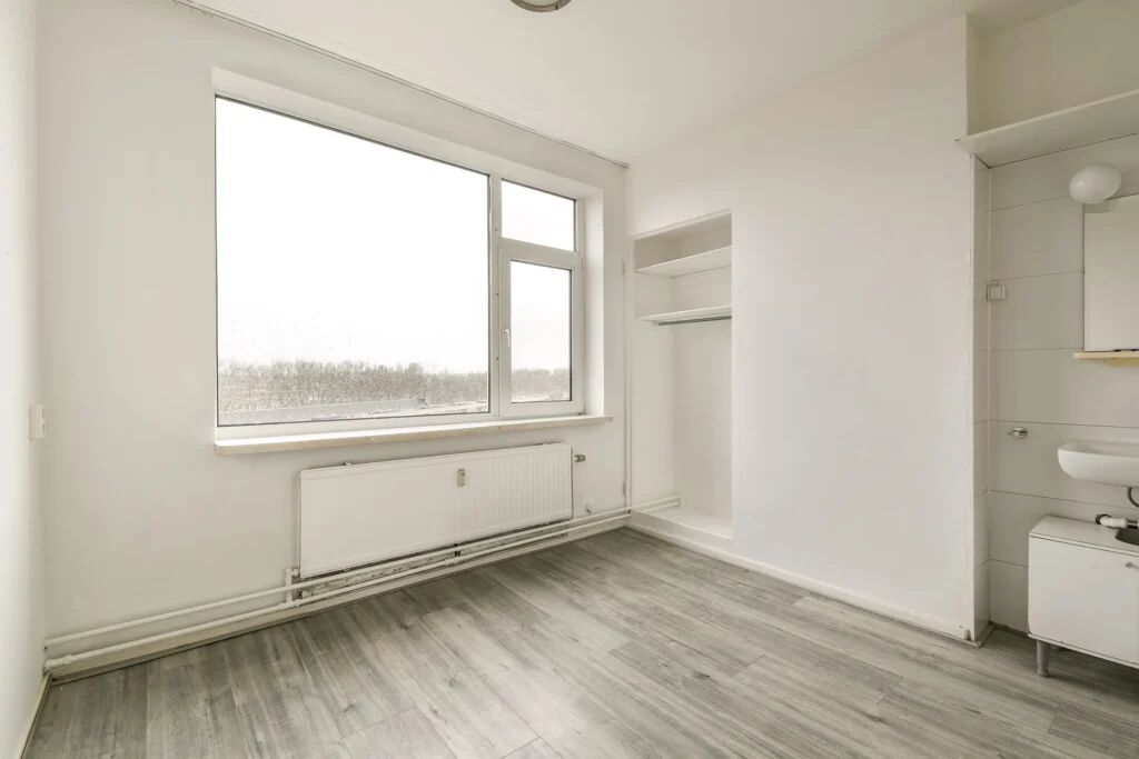 Een leeg appartement met een raam en inbouwkast.