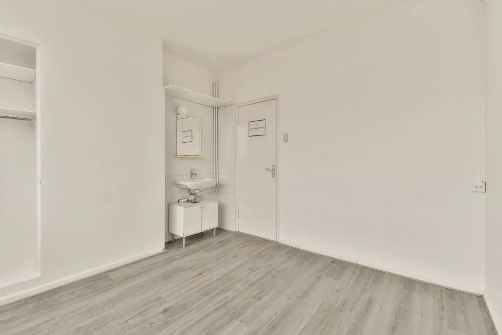 Een leeg appartement met een deur en wastafel