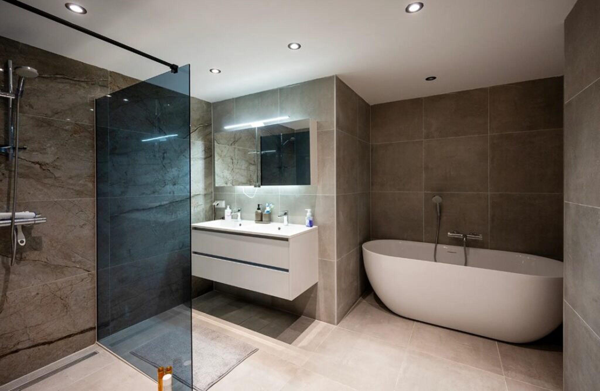 De badkamer met douche en ligbad.