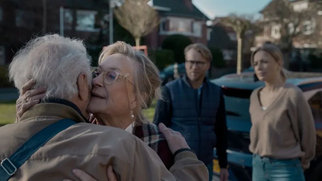 Een man en vrouw die elkaar een zoen op de wang geven.