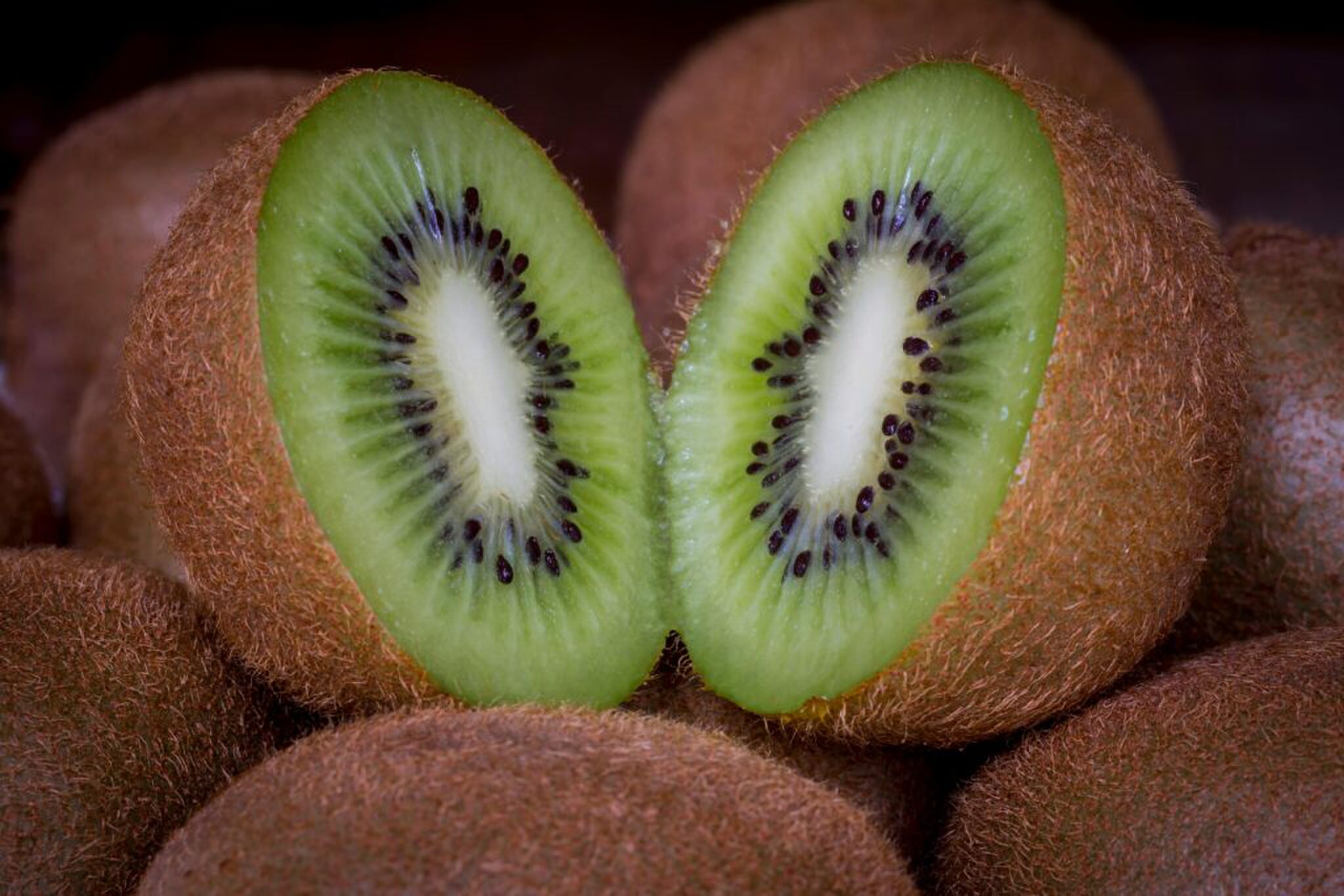 Een kiwi die doormidden is gesneden, met hele kiwi's eromheen.