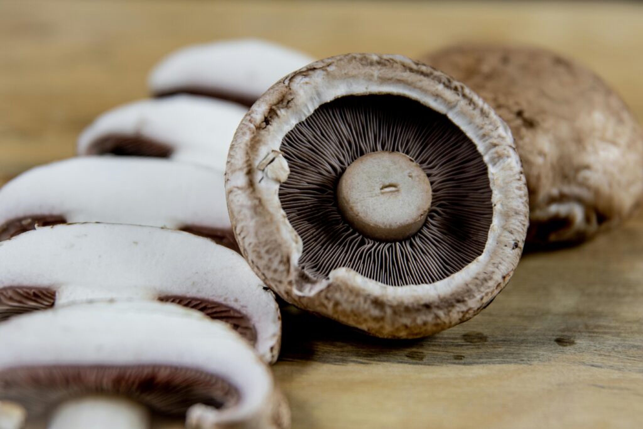 Een champigion die ligt op een snijplank in stukjes en twee hele.