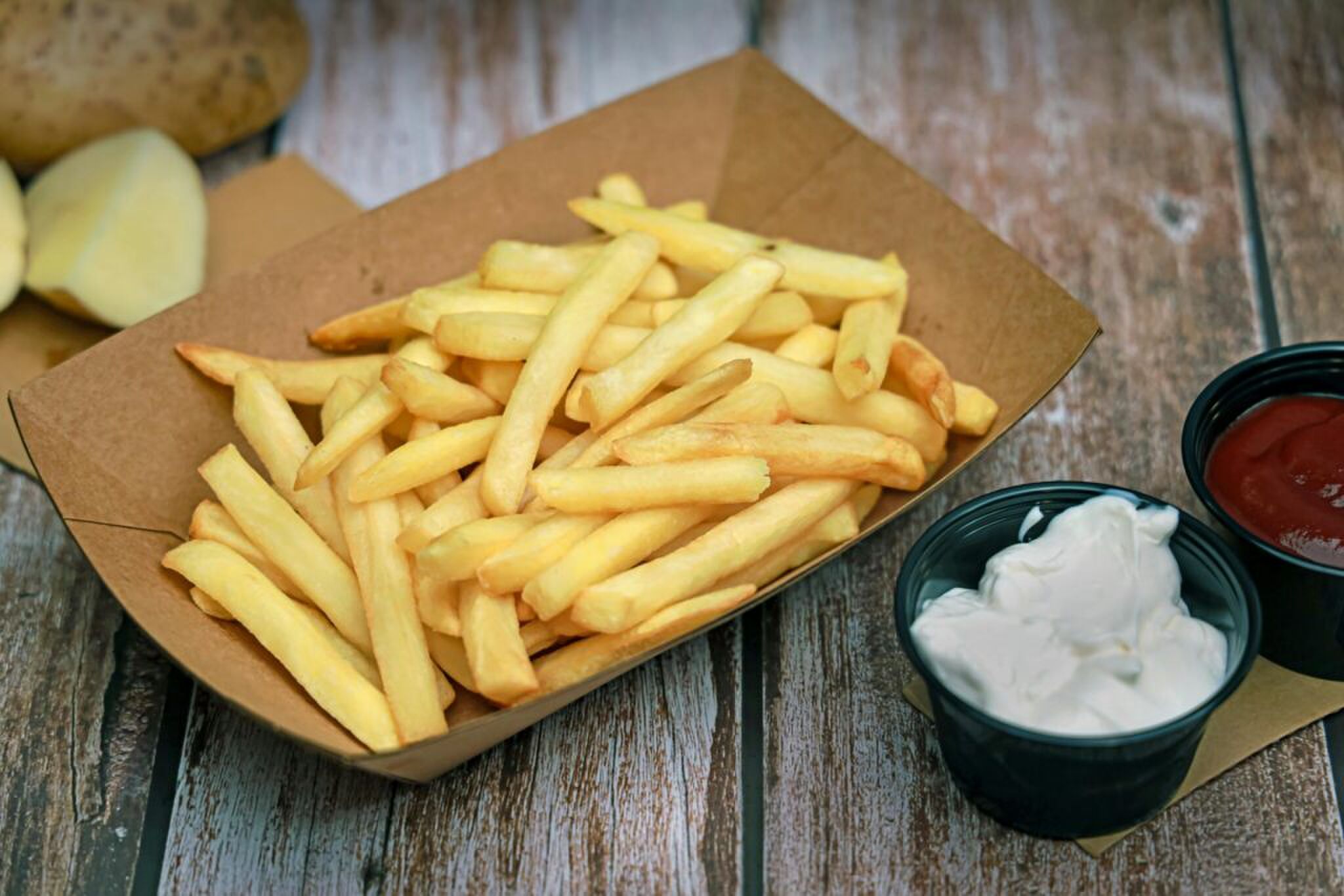 Een bakje friet met mayonaise en ketchup. 