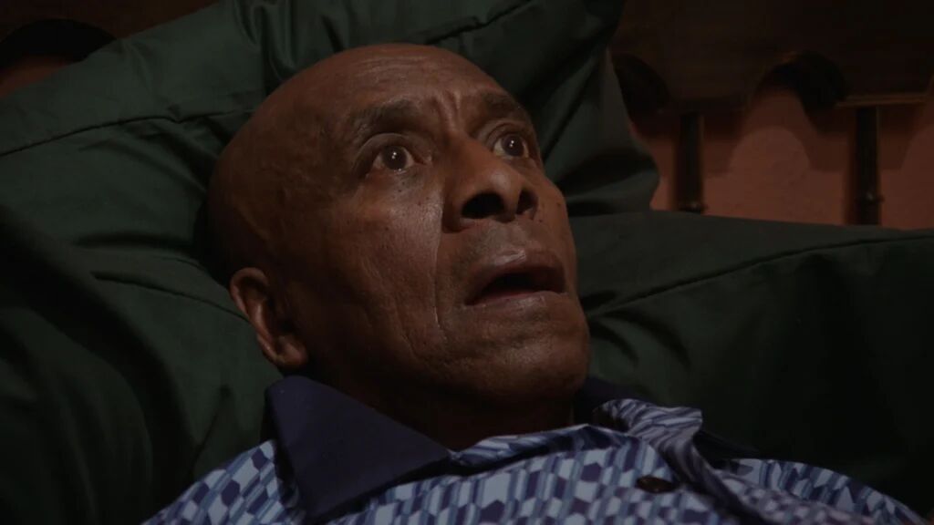 Een man die geschrokken op bed ligt.