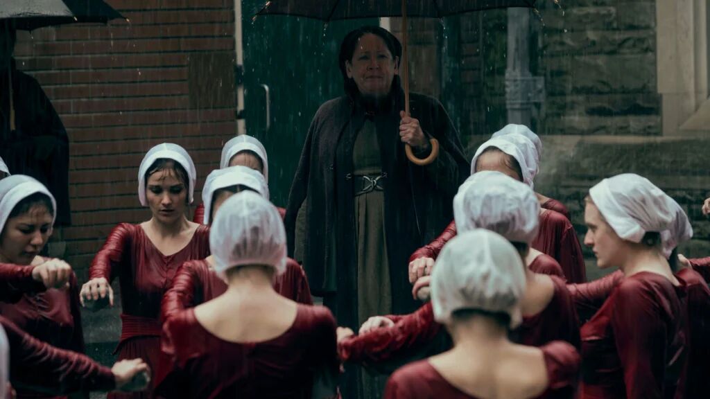 Vrouwen die in de regen staan met hun arm naar voren. 