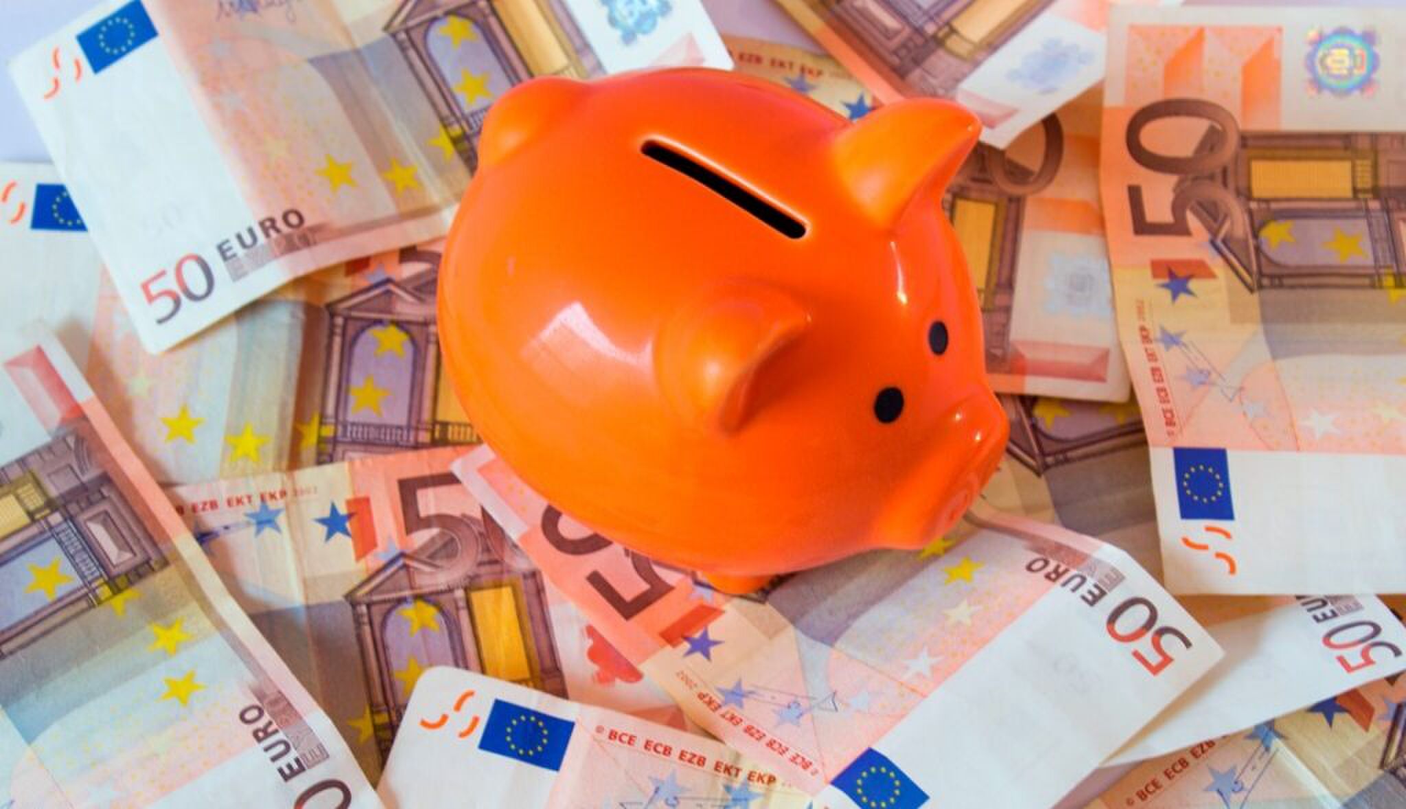 Een oranje spaarvarken op briefjes van 50 euro.