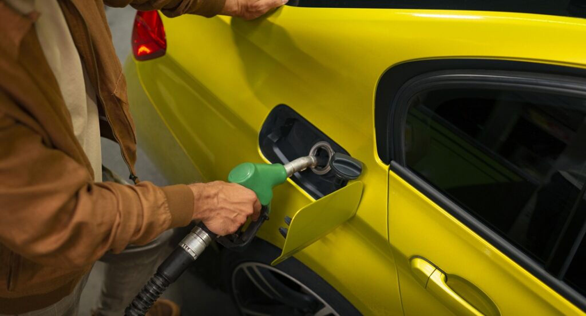 Een man die zijn auto aftankt.