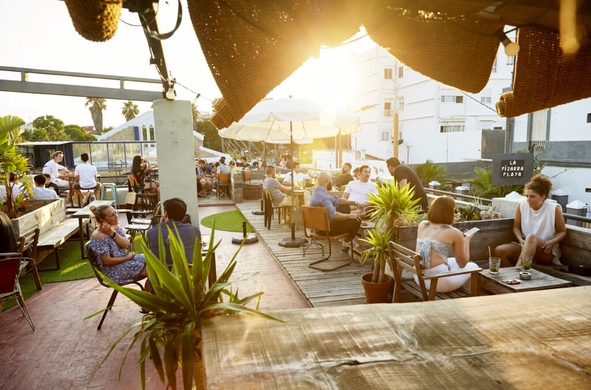 Een terras met mensen met een laag hangende zon.