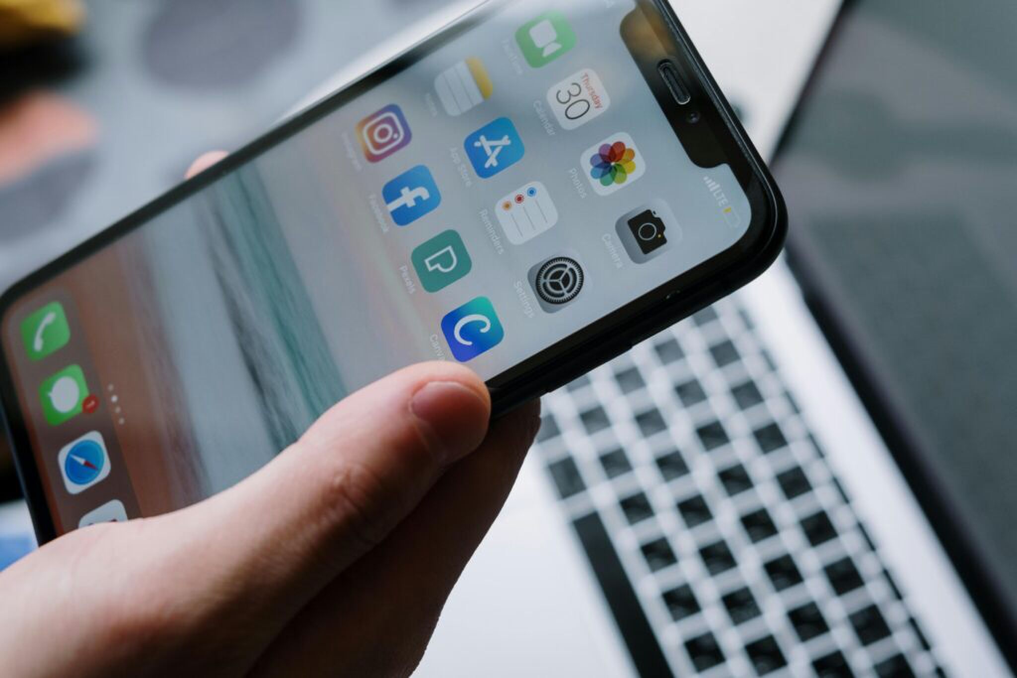 Een iPhone met op de achtergrond een laptop. 