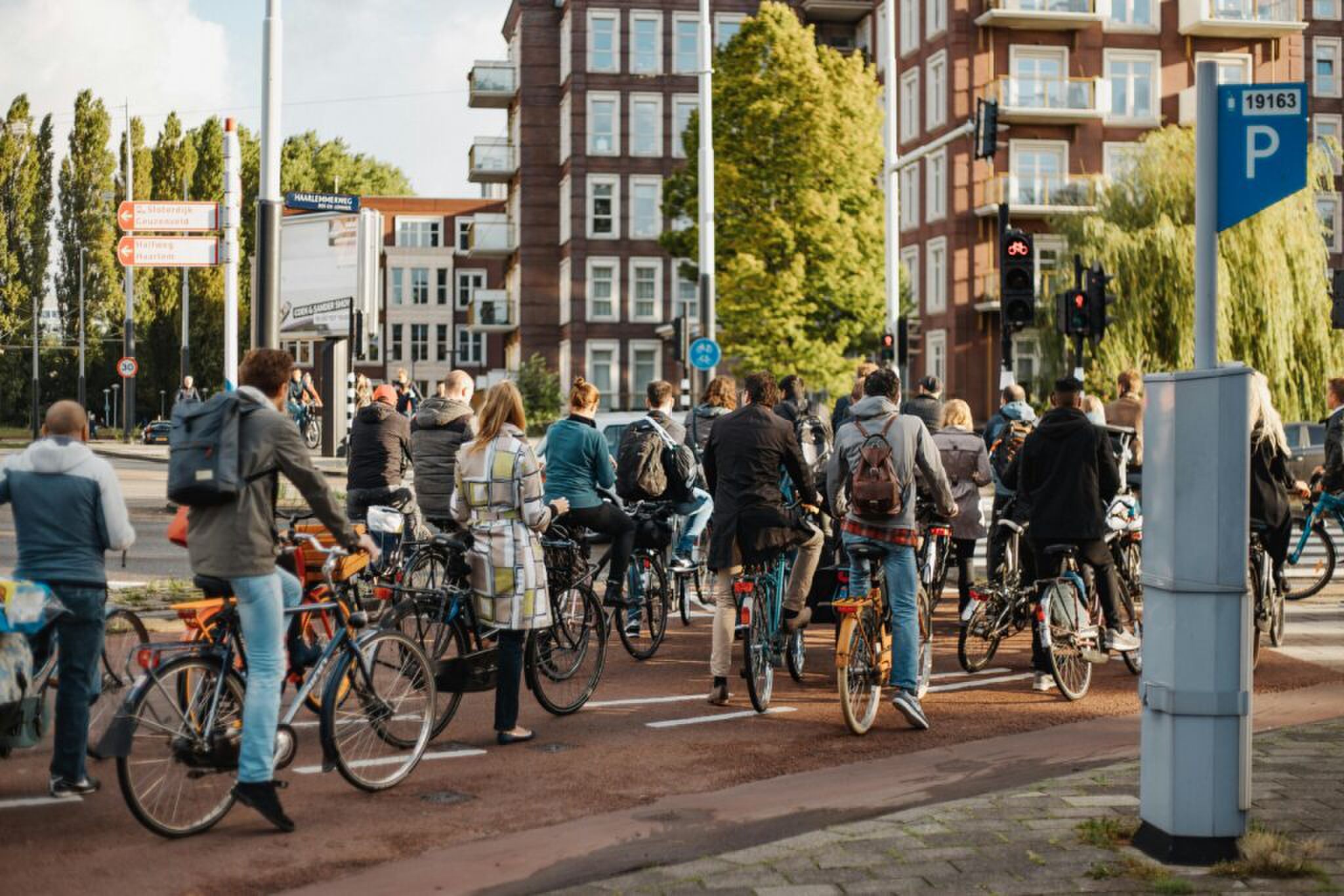 Een groep fietsers die wacht voor het stoplicht. 