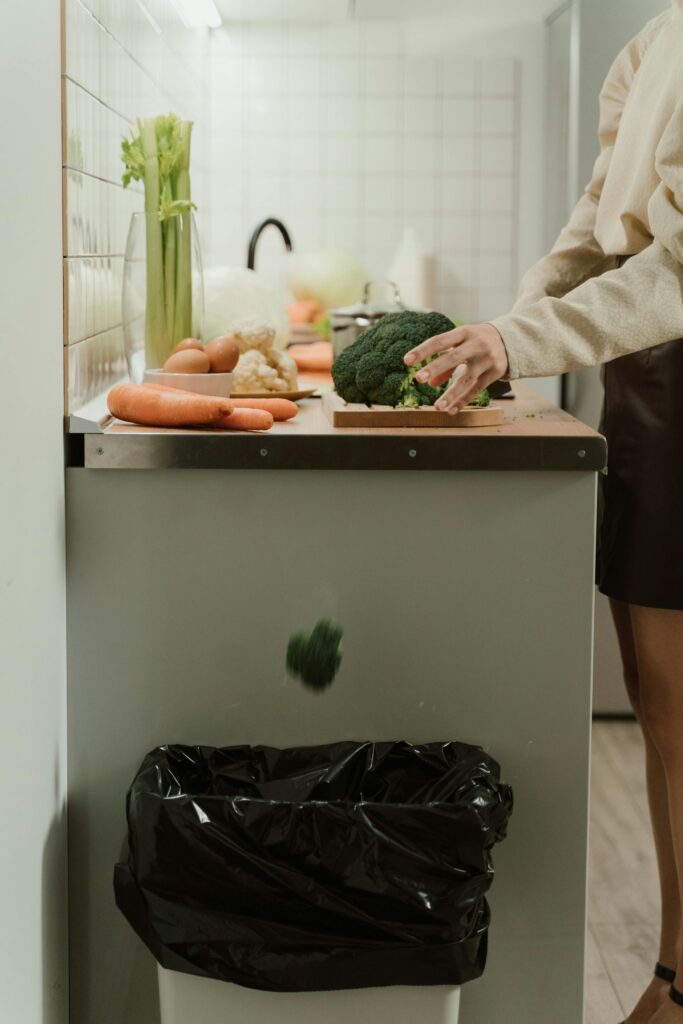 Iemand die een broccoli in de prullenbak gooit.