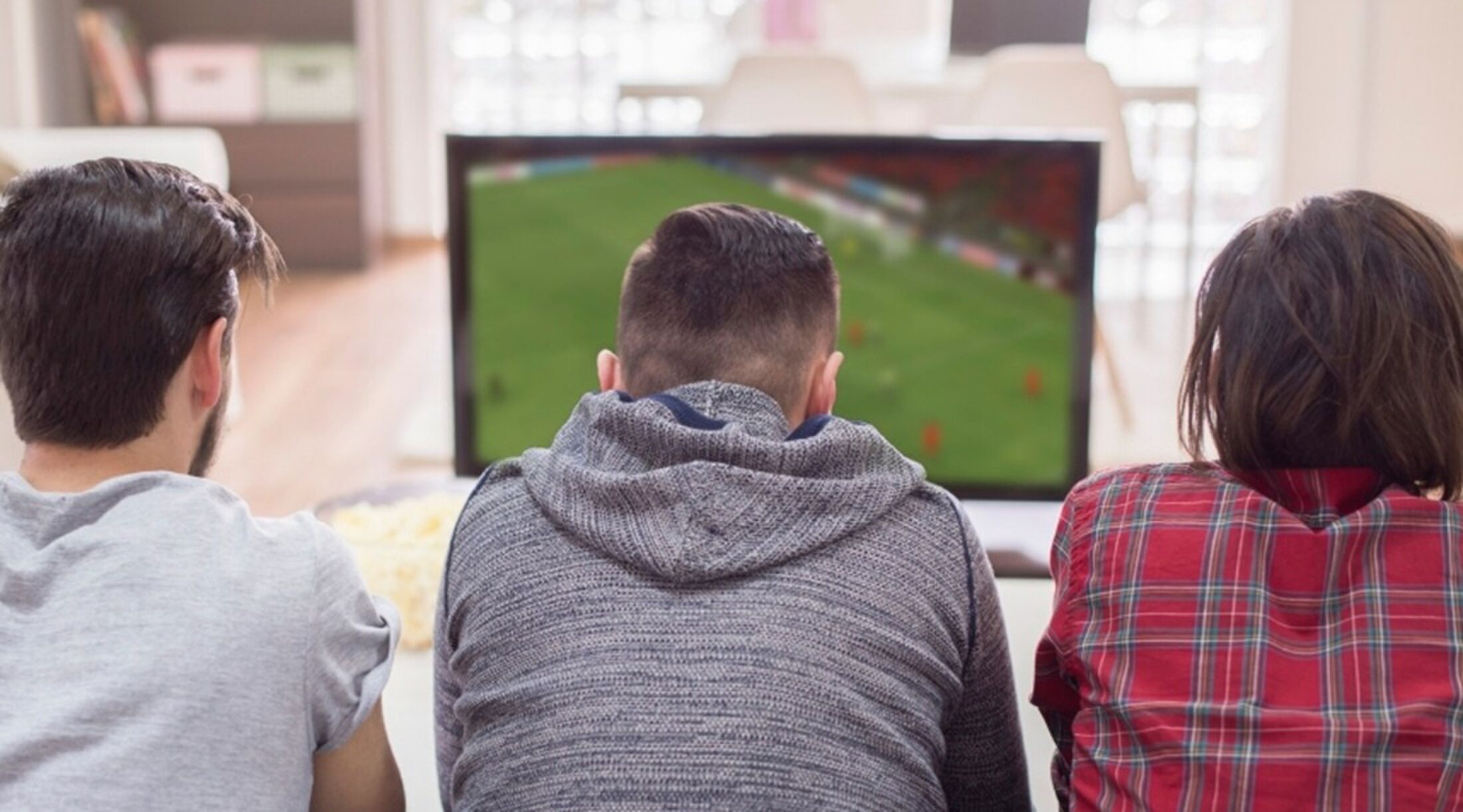 Drie mannen die voetbal kijken op een tv.