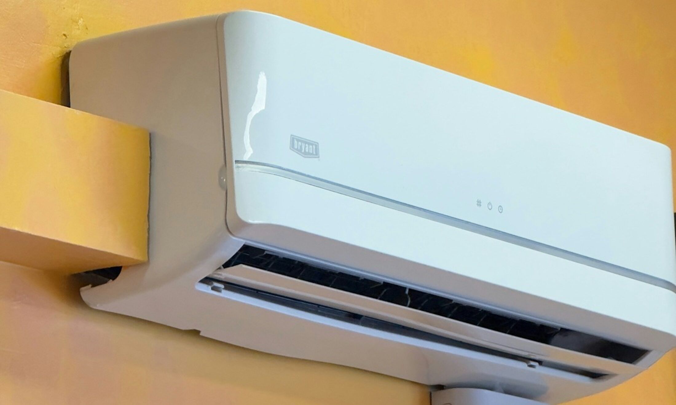 Een airco aan een gele muur.