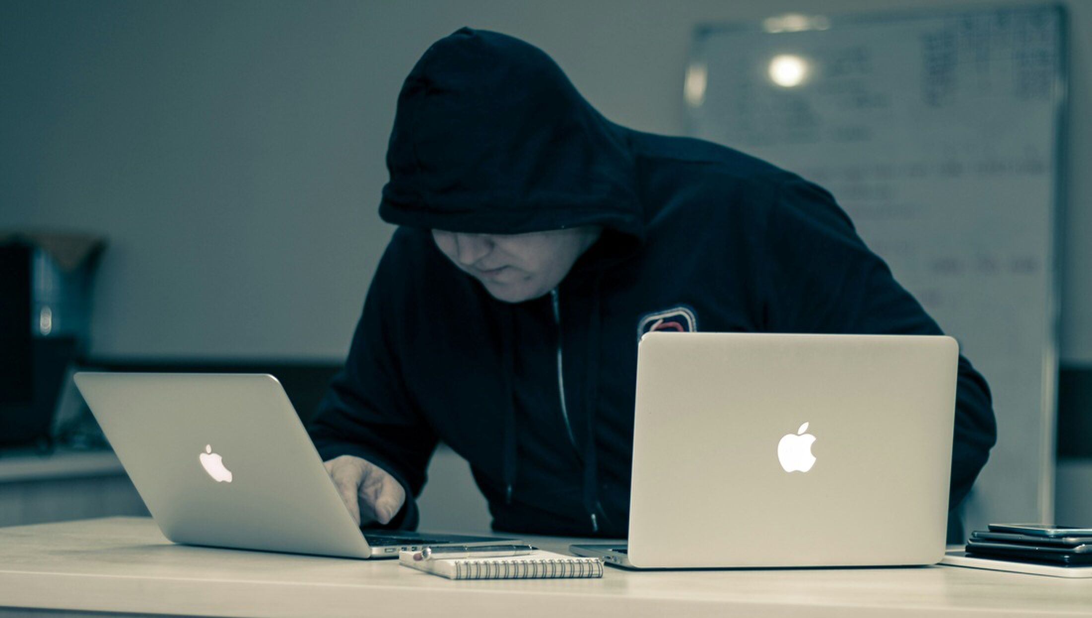 Een man die werkt op twee laptops.