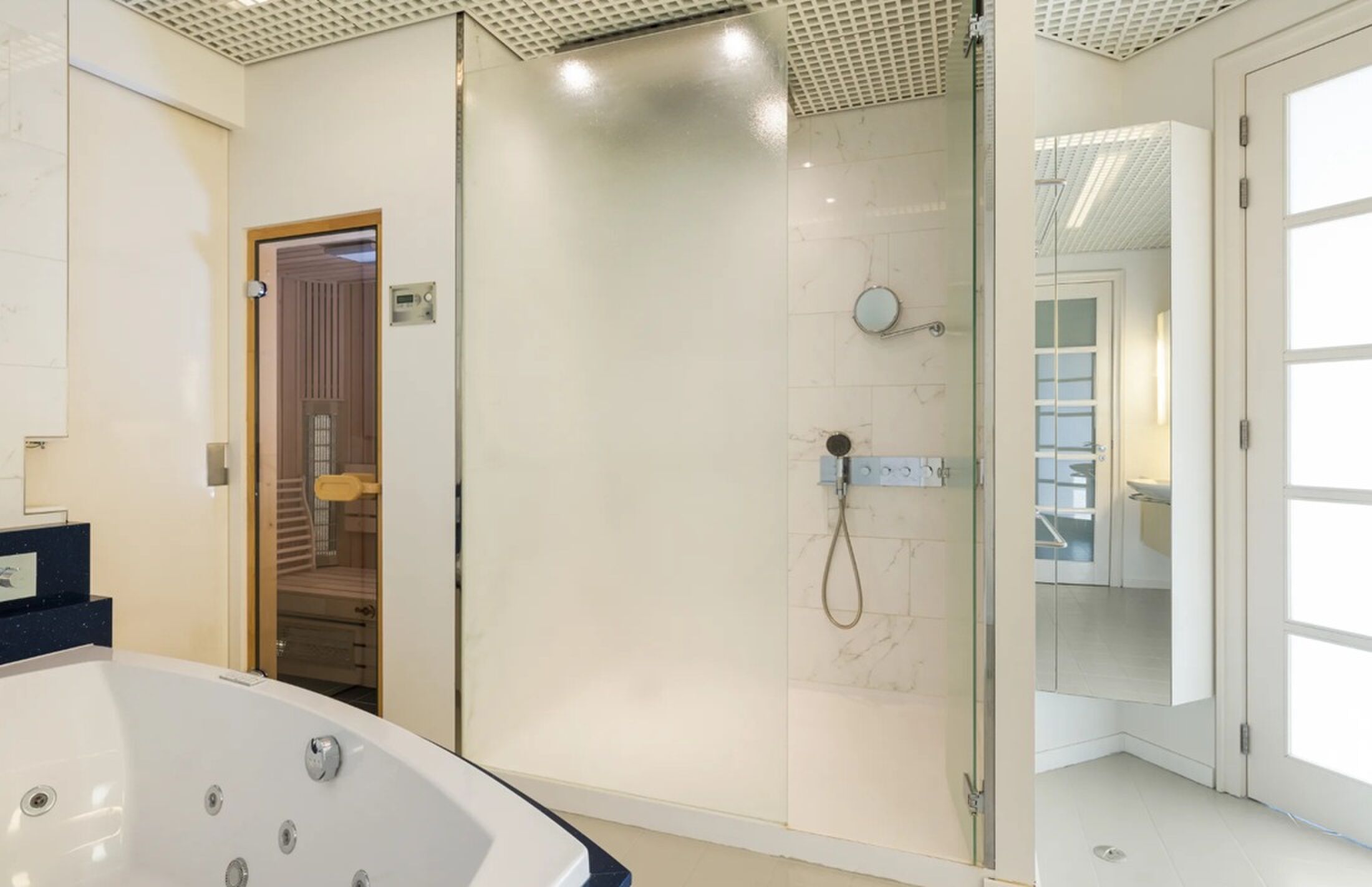 De badkamer met ligbad en sauna.