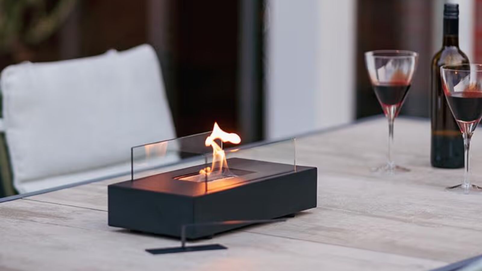 Een kleine tafelhaard die op een tafel staat met een vlammetje.