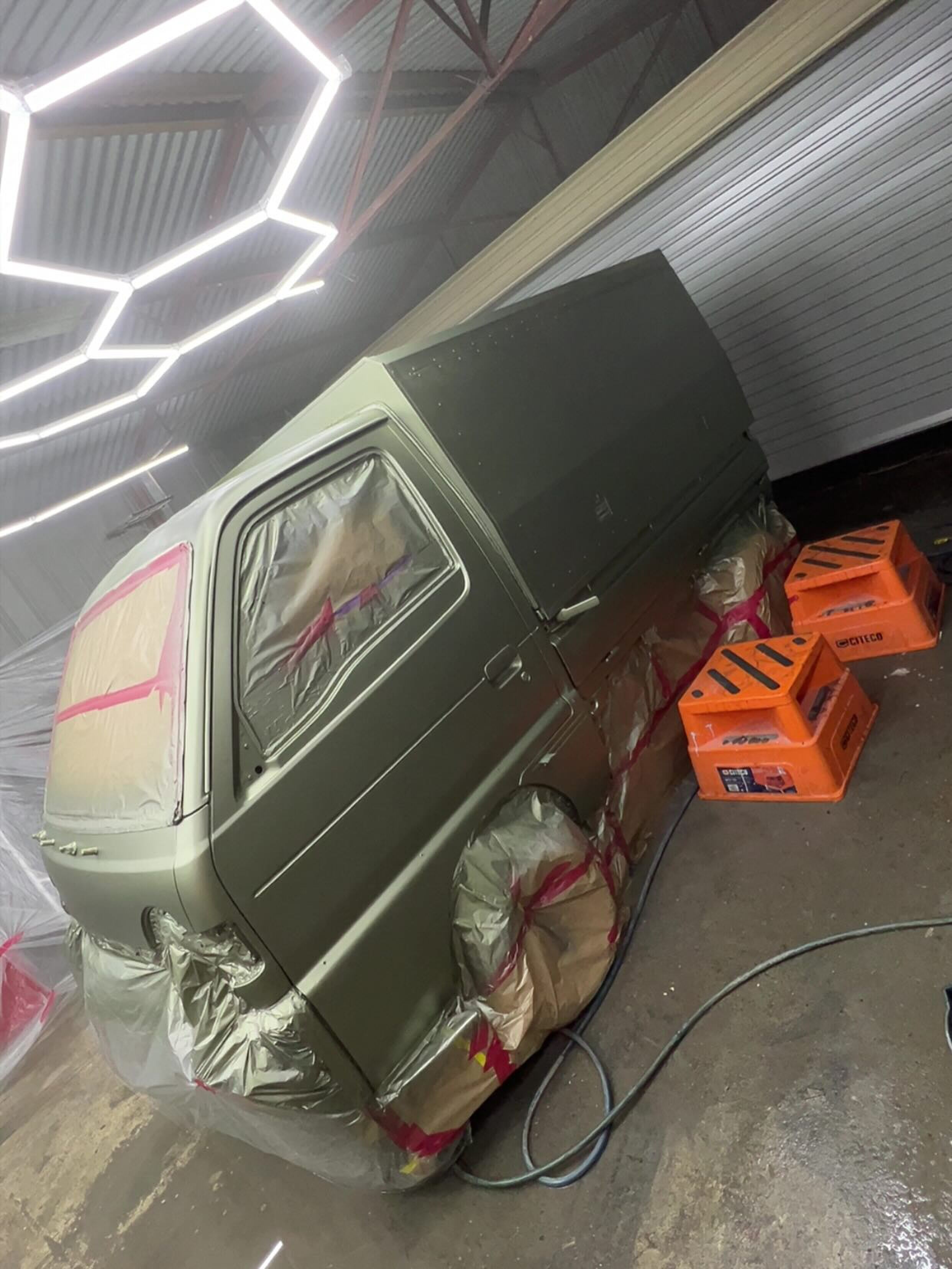 De omgebouwde Suzuki-camper wordt gespoten in een legergroene kleur