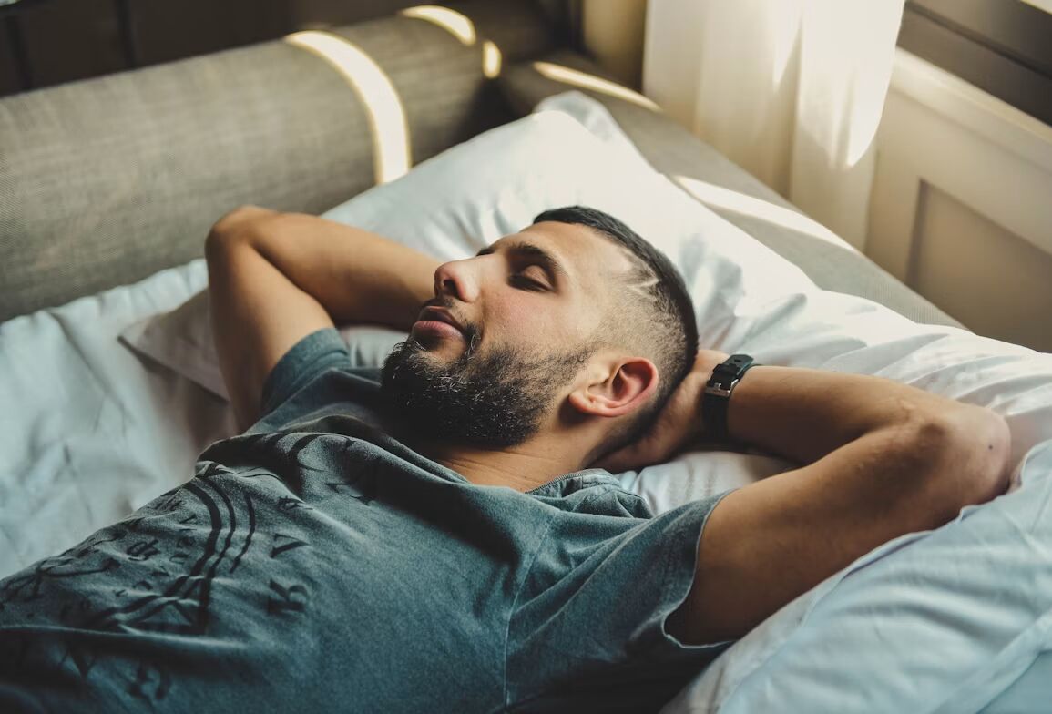 Man ligt op een bed een powernap te doen.