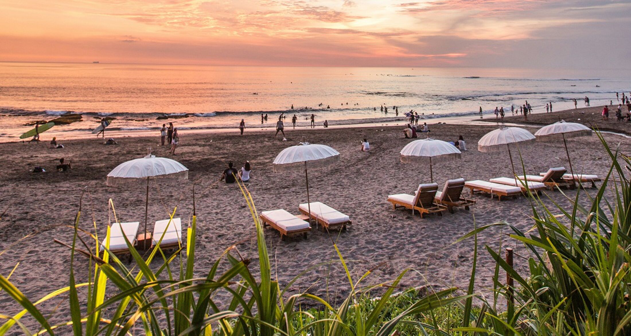 Een zonovergoten strand met ligbedden.