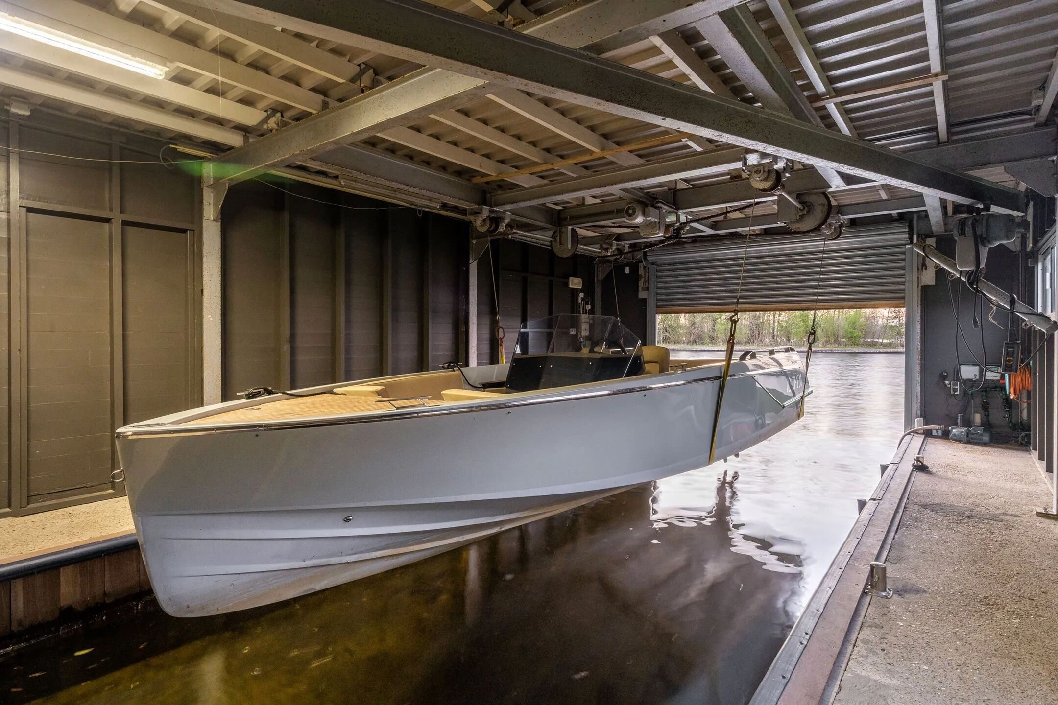 Een boothuis met een boot uit het water getild. 