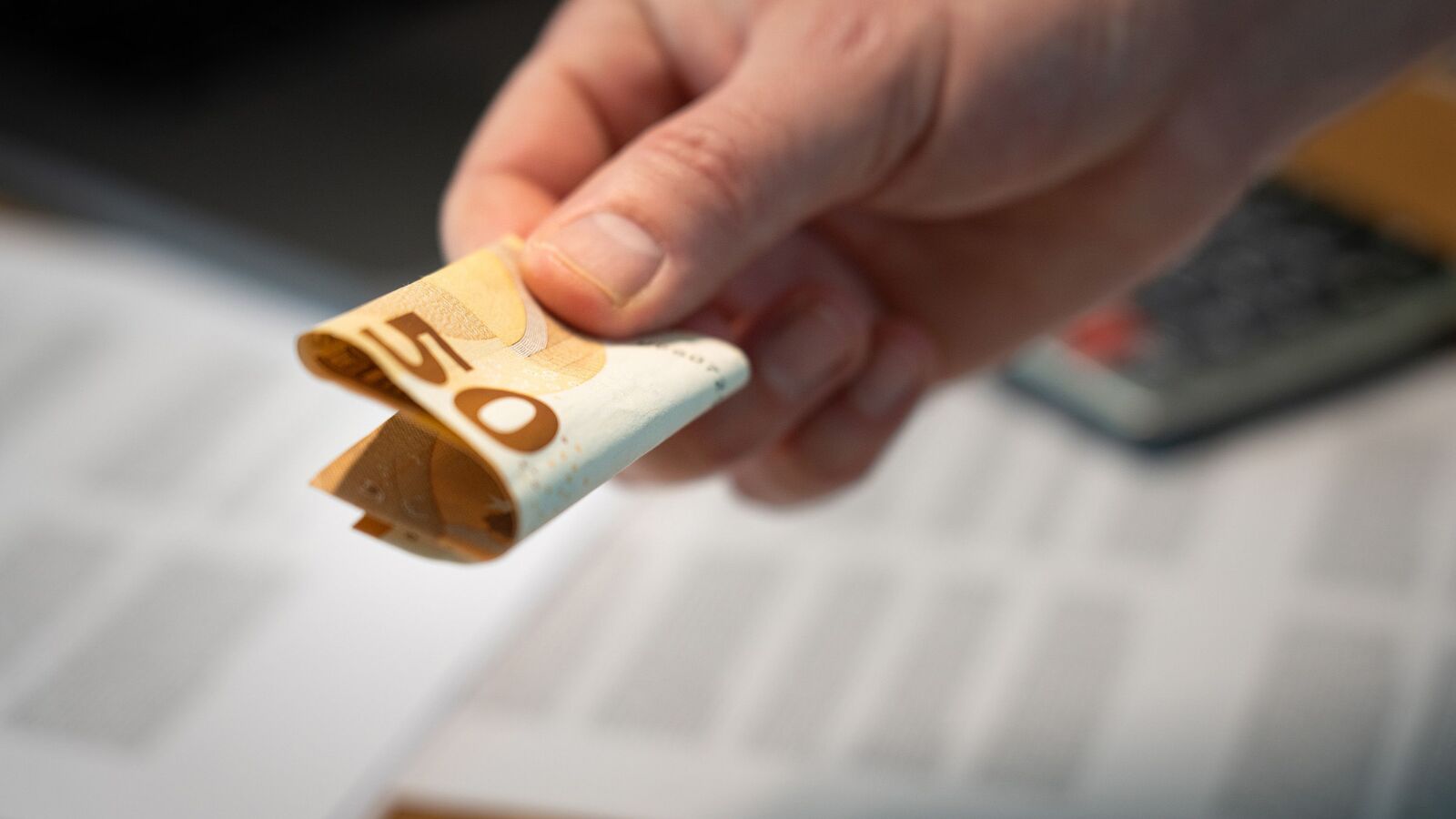 Iemand die een briefje van € 50 geeft.