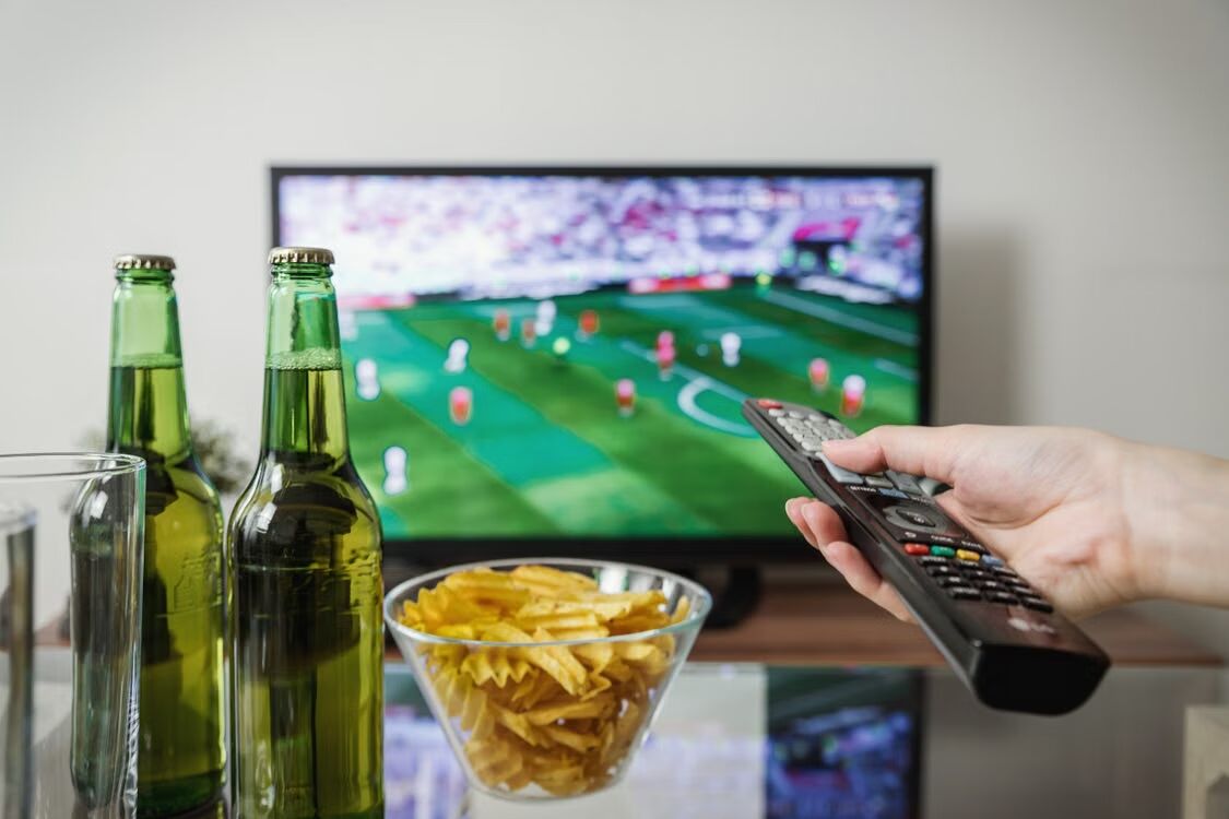 IPTV met afstandsbediening en drank en chips.
