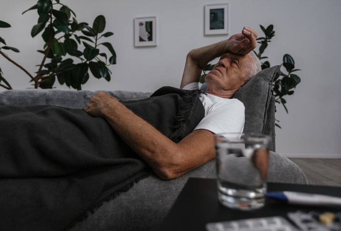 Man is heel ziek en ligt op de bank en heeft overduidelijk last van vrijetijdsziekte.