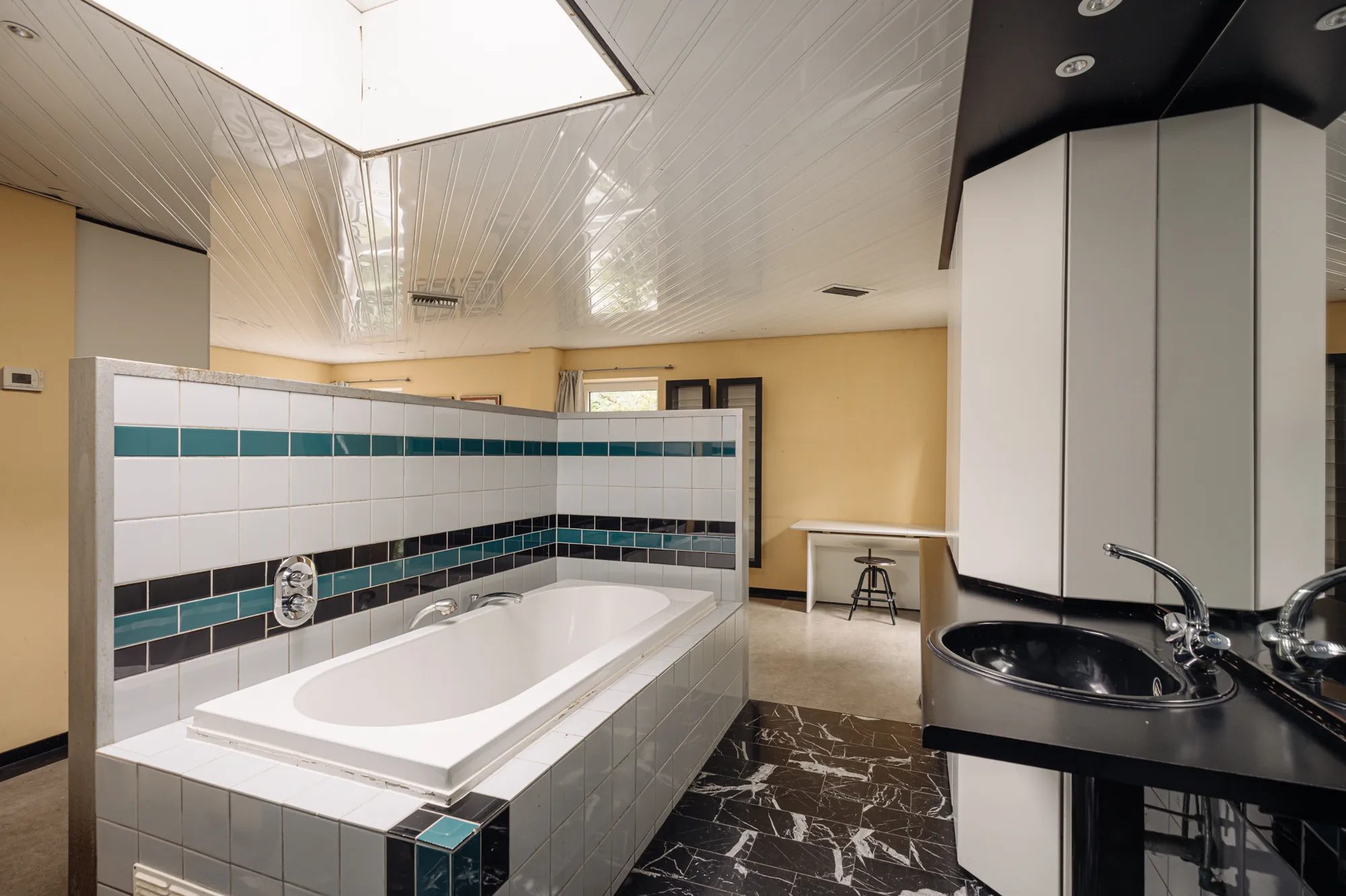 Een badkamer met ligbad en wastafel.