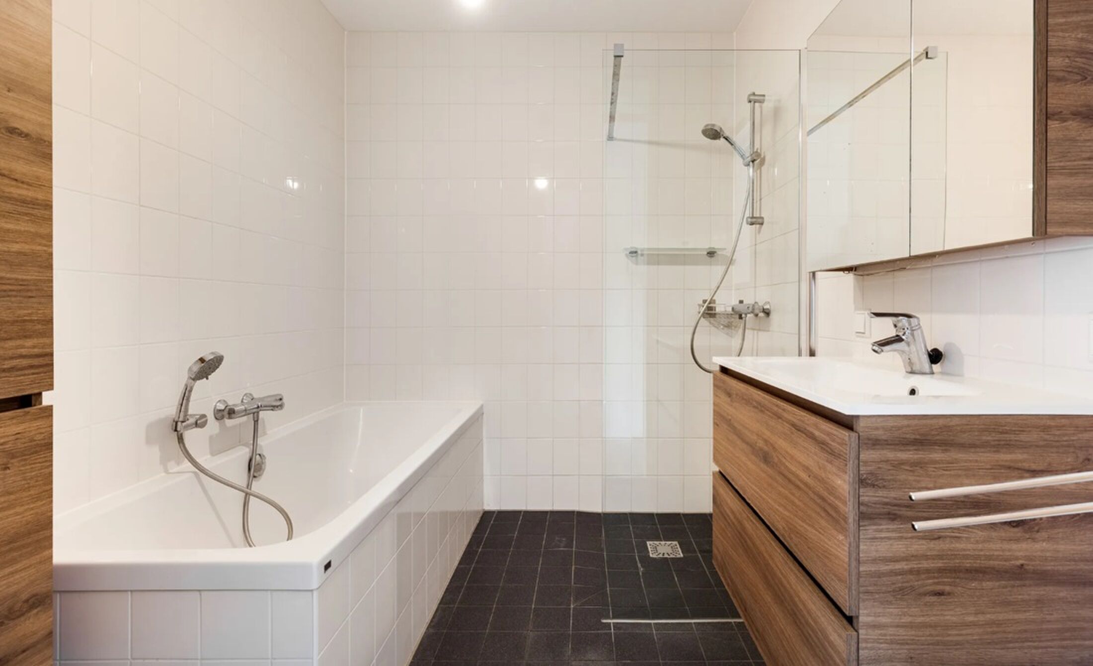 De badkamer met ligbad en douche.