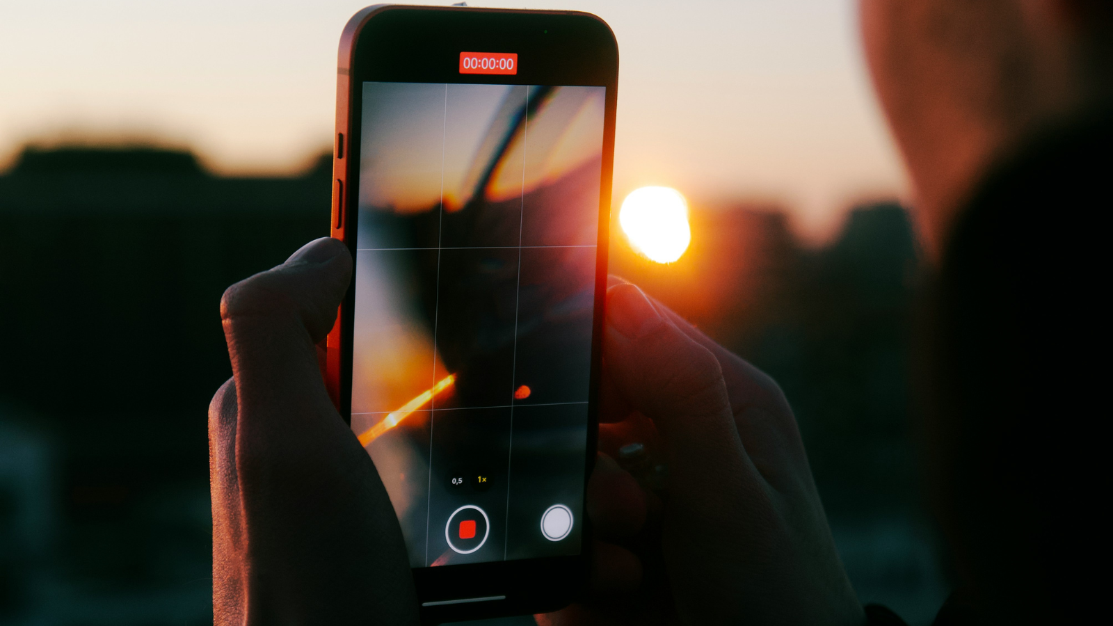 Iemand die met een iPhone de zonsondergang filmt. 