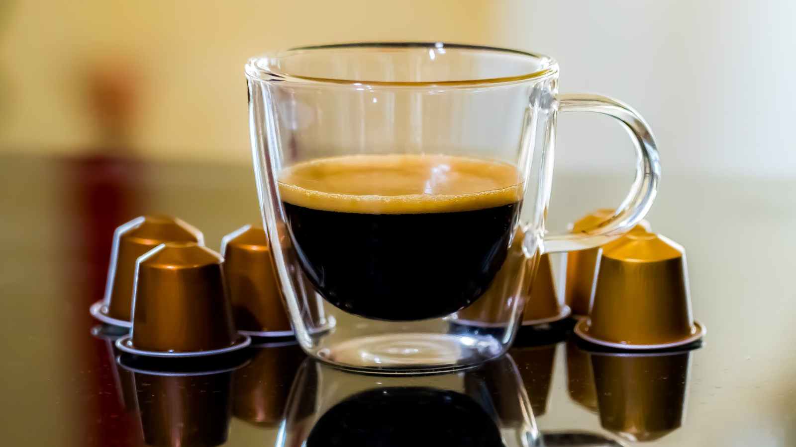 Een kopje koffie met koffiecups ernaast.