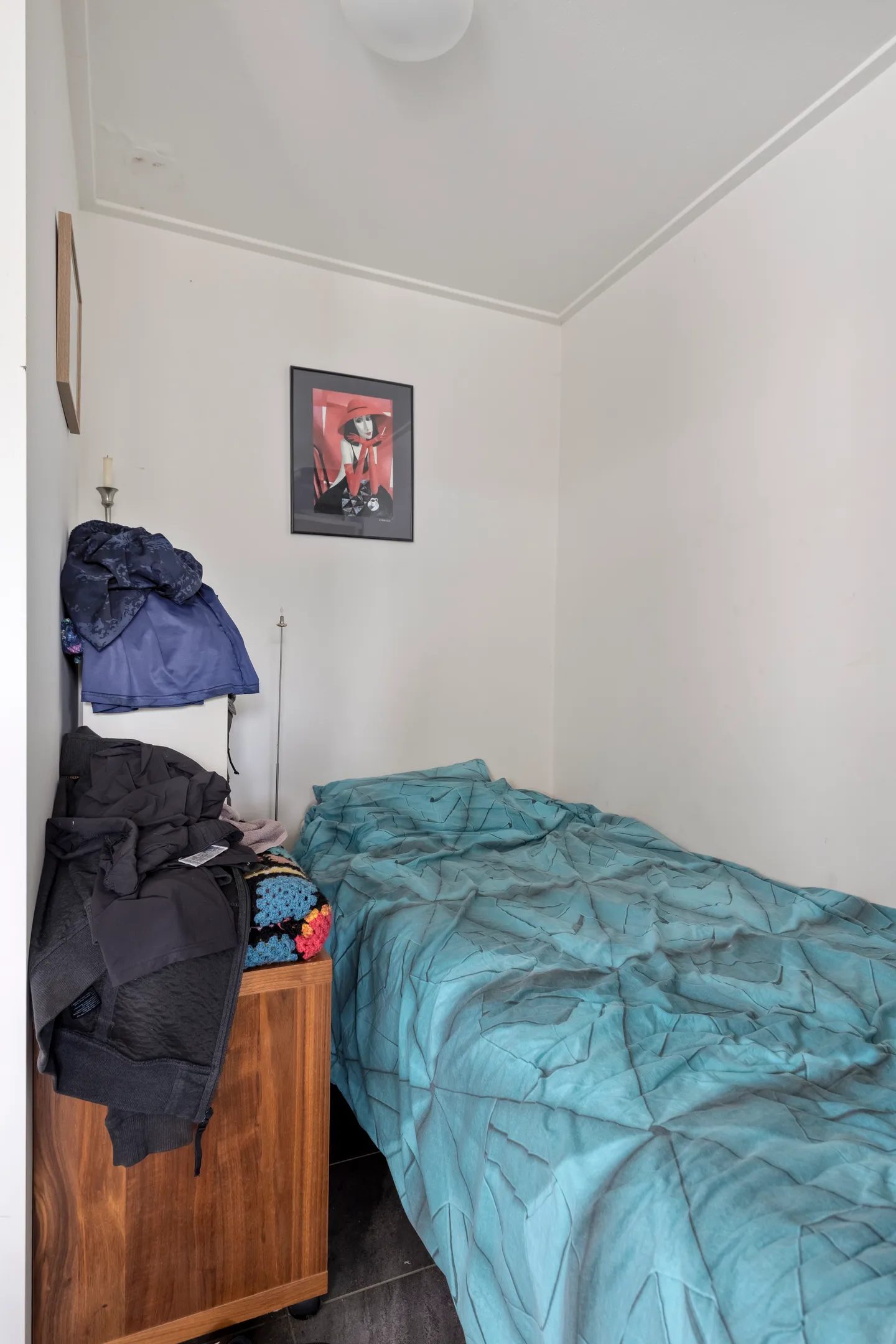 Een eenpersoonsbed met schilderij aan de muur.