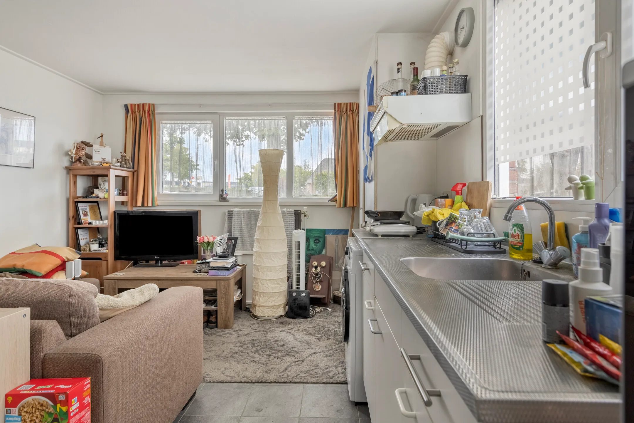 Een woonkamer met tv, stoel en kast.