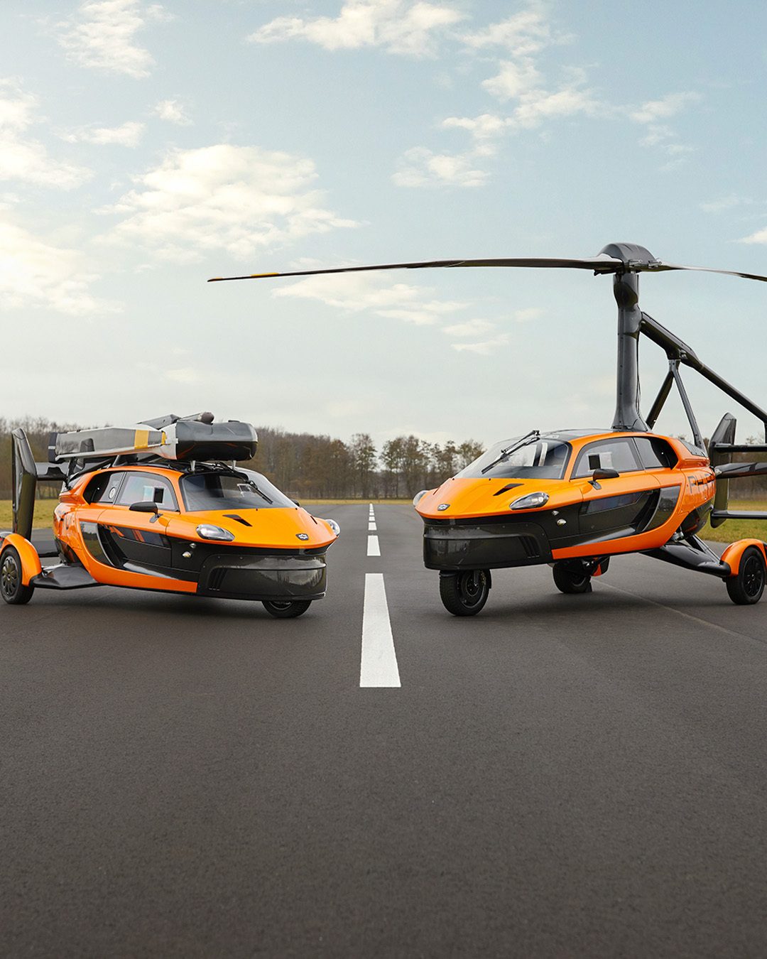 Twee oranje vliegende auto's die staan op een startbaan.